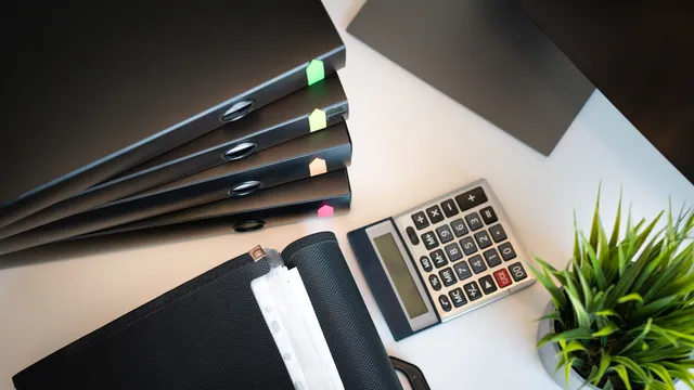 Tomt kontorbord med arkivmappe, papirer og en lukket bærbar computer