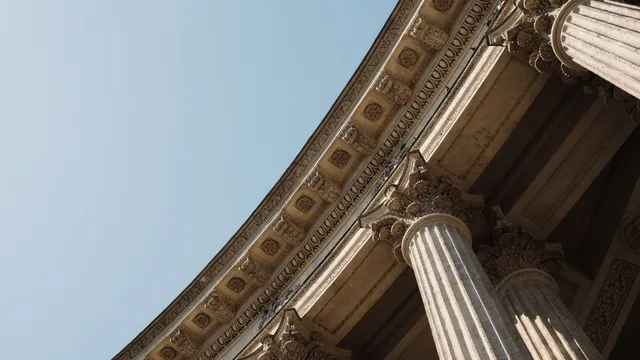 Klassiske søjler på en gammel bankbygning set nedefra mod en klar himmel