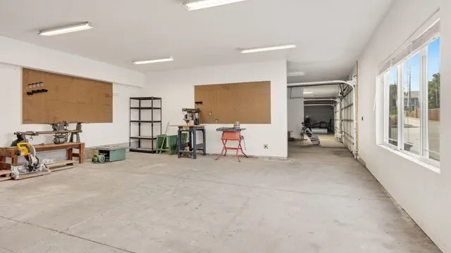 Lyst værkstedslokale med værktøj på tavler og tomme arbejdsborde