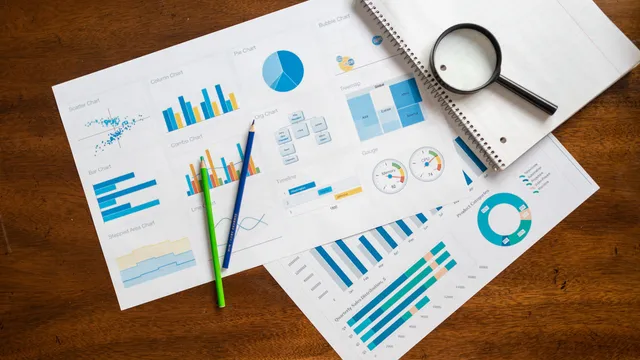 Skrivebord set ovenfra med finansielle diagrammer, lup og kontorartikler