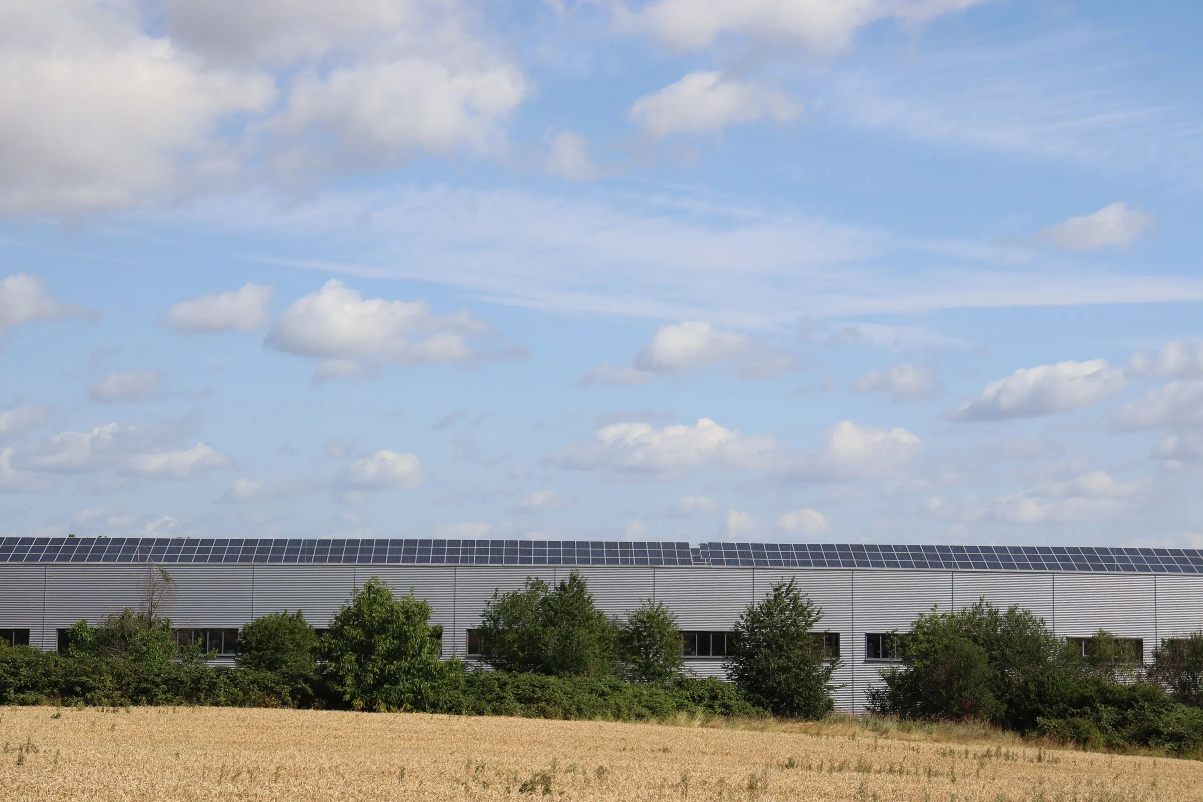 Lagerbygning på landet med solceller på taget under blå himmel