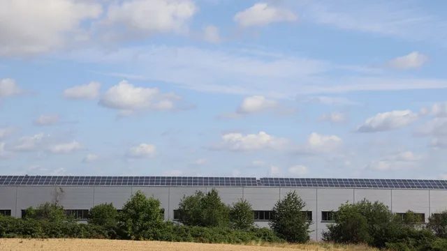 Lagerbygning på landet med solceller på taget under blå himmel
