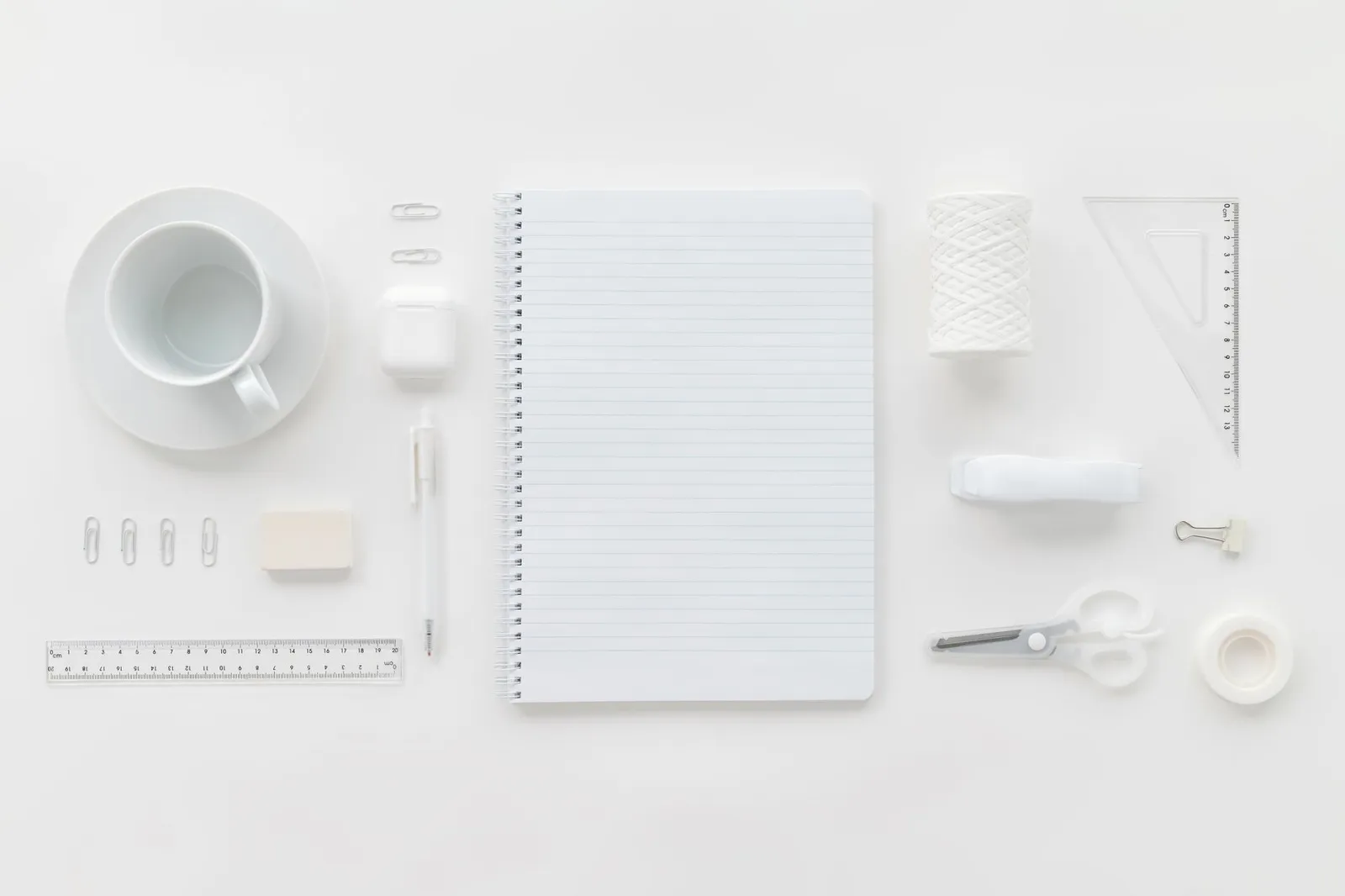 Kontorartikler med notesblok, lineal og en kop kaffe set ovenfra