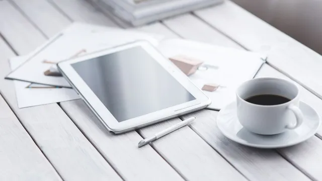 Skrivebord med tablet, papirer og en kop kaffe