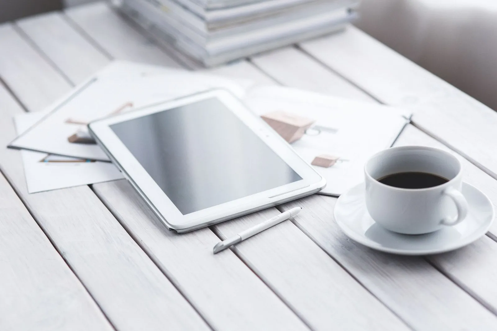 Skrivebord med tablet, papirer og en kop kaffe
